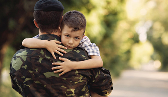 A service member hugging a child